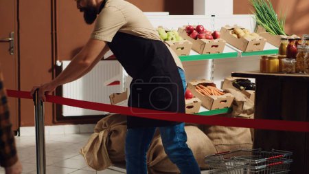Photo for Vendor greeting first customers at zero waste supermarket grand opening ceremony, removing red ribbon. Storekeeper welcoming shoppers inside eco friendly local neighborhood store - Royalty Free Image