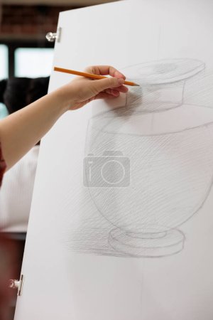 Foto de Mujer estudiante o escuela de arte dibujo jarrón realista en lápiz, bocetos en papel durante la lección, el aprendizaje de las técnicas de sombreado a lápiz. La gente aprende a dibujar para entrenar la creatividad en la edad adulta - Imagen libre de derechos