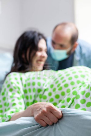 Foto de Esposo reconfortando a la mujer embarazada durante el parto en la sala de hospital, futura madre gritando y empujando durante la cirugía de cesárea. Paciente con embarazo que entra en trabajo de parto en la clínica de maternidad - Imagen libre de derechos