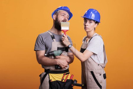 Photo for Construction workers yawning and being sleepy in studio, posing with multiple renovating tools. Exhausted repairman and handywoman holding building instruments, being tired and asleep. - Royalty Free Image