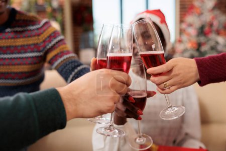 Téléchargez les photos : Travailleurs mains cliquetis verres remplis de vin mousseux tout en célébrant Noël au bureau. Collèges boire de l'alcool, griller et profiter festif Nouvel An vacances gros plan - en image libre de droit