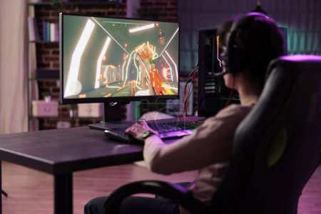 Photo for Professional streamer playing videogames on gaming pc, streaming live action competition online. Gamer enjoying game at computer desk, showcasing impressive skills in front of internet fans - Royalty Free Image