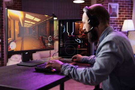 Photo for Gamer using expert grade level gaming computer to avoid disruptive lag while playing esports competitions. Man relaxing at home playing action shooter videogame late at night - Royalty Free Image