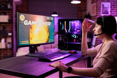 Photo for Frustrated gamer losing singleplayer spaceship arcade racing videogame, seeing game over screen on gaming computer display. Woman being dissapointed after being defeated on difficult game level - Royalty Free Image