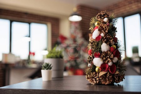 Photo for Decorated artificial christmas tree with ornaments and houseplant in festive office workplace closeup. Winter celebration season adornments in corporate workspace selective focus - Royalty Free Image