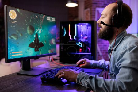 Photo for Gamer playing classic arcade action space videogame, shooting meteorites using lazer beams. Man enjoying leisure time at home using high tech gaming PC to solve missions in singleplayer game - Royalty Free Image