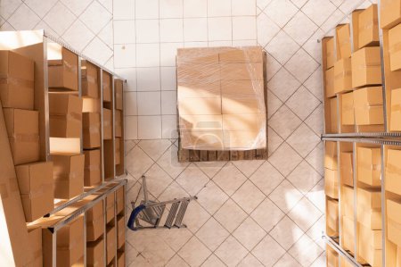 Photo for Empty stockroom full with metallic shelves and carton boxes, waiting for workers to come and work at clients orders. Storage room with nobody in it ready for packages delivery. Warehouse concept - Royalty Free Image