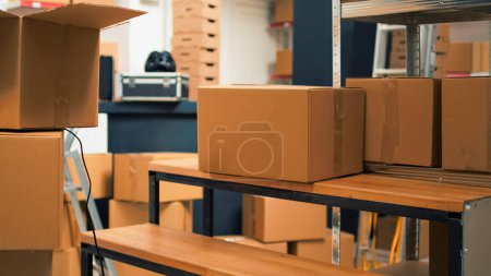 Foto de Startup storehouse filled with merchandise to ship to clients, products in cardboard packages used for business development. Empty storage room with carton boxes and stacks of supplies. - Imagen libre de derechos