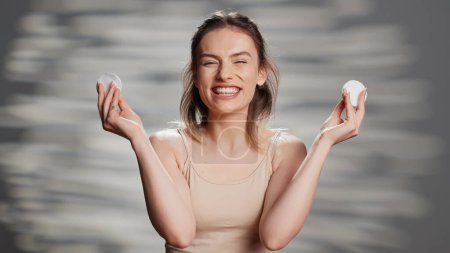 Photo for Confident silly girl having fun with cotton pads on camera, using skincare accessories to promote beauty routine and self love. Young flawless woman acting natural and funny for ad. - Royalty Free Image