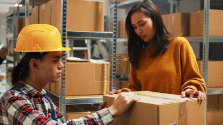 Photo for Asian man planning shipment of orders in storage room, working with female employee to send packages for supply chain. Team of people checking merchandise and products, small business. - Royalty Free Image
