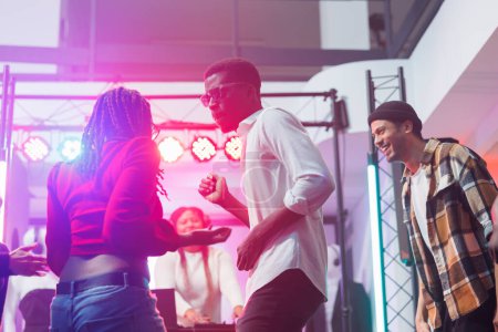 Foto de Bailarines afroamericanos pareja improvisando movimientos en discoteca de música electrónica en vivo en discoteca. Enérgicos jóvenes bailando y festejando en la pista de baile en el club - Imagen libre de derechos