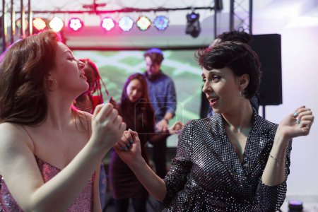 Foto de Mujeres caucásicas jóvenes bailando en la actuación de música en vivo en discoteca. Dos novias de fiesta y discotecas en la pista de baile juntas, disfrutando de la actividad de entretenimiento de la vida nocturna - Imagen libre de derechos