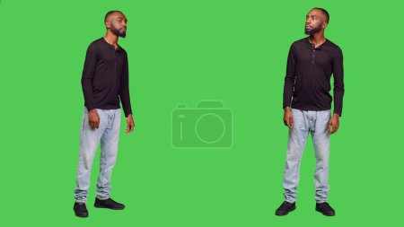Photo for Relaxed friendly person smiling in front of camera, feeling positive and confident over full body green screen background. Young man being cheerful and optimistic standing in studio. - Royalty Free Image