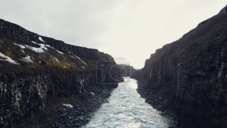 Téléchargez les photos : Vue aérienne de la chute d'eau du golfe nordique, fantastique ruisseau fluvial coulant entre des collines rocheuses. Spectaculaire cascade glaciaire descendant des falaises, paysage scandinave. Mouvement lent. - en image libre de droit