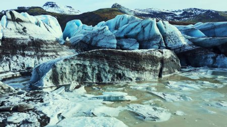 Téléchargez les photos : Vue aérienne de la crevasse dans la banquise, d'énormes blocs de glace et des grottes sombres sur la calotte glaciaire du vatnajokull. icebergs en forme de diamant et lagune de glacier créant un paysage nordique avec lac. Mouvement lent. - en image libre de droit