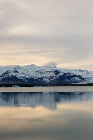 Isländische gefrorene Region mit Teich im skandinavischen Stil und schneebedeckten Bergen. Polar Adventure Road durch das kühle Paradies mit spektakulärem Sonnenuntergang in goldener Stunde.