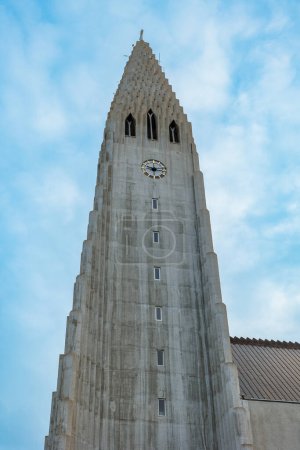 Foto de Catedral de Hallgrimur en Islandia de pie majestuoso como torre de la religión con la cruz santa, monumento sagrado arquitectónico nórdico. Enorme Hallgrimskirkja iglesia en la capital icelándica, la fe luterana. - Imagen libre de derechos
