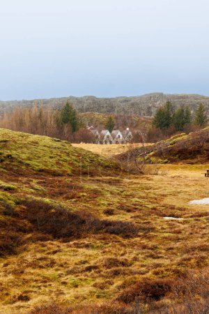 Foto de Parque nacional escandinavo en iceland lleno de colinas y campos, magníficas casas rurales cerca del arroyo del río en thingvellir. Hermosa ruta panorámica y puntos de referencia nórdicos naturales. - Imagen libre de derechos