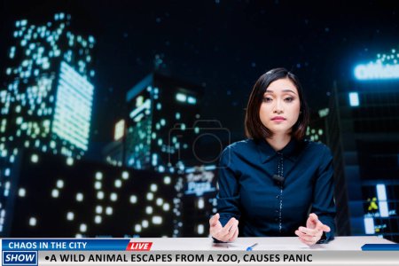 Photo for Newscaster warns people of wild animal which escaped from local zoo, frightening population and causing panic in the city. Asian woman going live on night show, wildlife escape. - Royalty Free Image