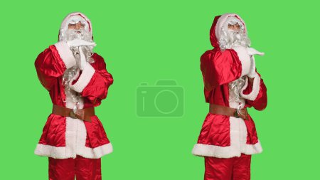 Foto de San Nick cosplay muestra símbolo de tiempo de espera, posando en traje de temporada festivo sobre fondo de pantalla verde. Joven que representa la Navidad del padre pidiendo un descanso, hace señal de pausa. - Imagen libre de derechos