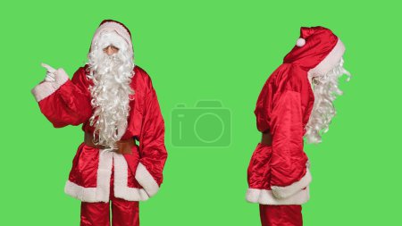 Téléchargez les photos : Père Noël dit non en studio, être déçu par les enfants coquins debout sur fond d'écran vert. Personne portant costume santa claus festif, acte frustré et mécontent. - en image libre de droit