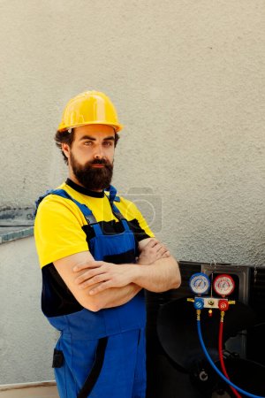 Photo for Portrait of capable repairman standing in front of repaired outdoor hvac system, proud of work done. Meticulous expert hired by home owner happy with easy fixing of condenser parts - Royalty Free Image