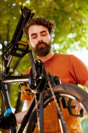 Photo for Close-up of caucasian male cyclist securing his bike wheel ensuring a safe and enjoyable recreational cycling experience. Outdoor activity of young athletic man maintaining bicycle tire and chain ring - Royalty Free Image