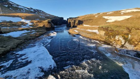 Foto de Espectacular valle natural icelandés con grandes colinas y crestas rocosas, cañón del río fjadrargljufur en Islandia, rocas y laderas cubiertas de nieve. Paisaje ártico paisaje salvaje en el norte. - Imagen libre de derechos