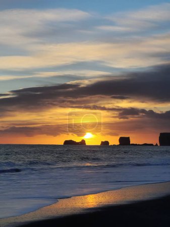 Téléchargez les photos : Fantastique scène nordique avec front de mer en iceland, littoral de l'océan rayonnant au coucher du soleil à côté de la plage de sable noir. Pays nordique avec vue imprenable sur la nature et cadre pittoresque. - en image libre de droit
