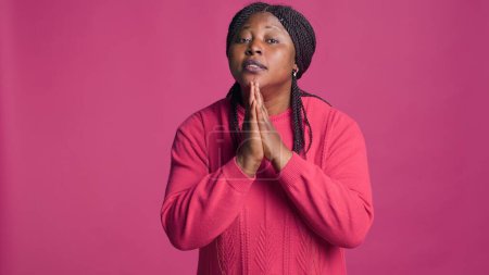 Photo for Young african american female earnestly begging with her hands together while looking at camera. Beautiful black woman with body language of pleading and requesting. - Royalty Free Image