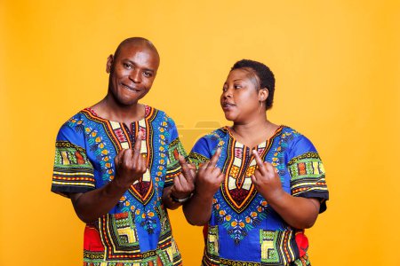 Photo for Rude african american couple showing middle finger gesture and looking at camera with angry expression. Furious man and woman demonstrating offensive and bad behavior studio portrait - Royalty Free Image