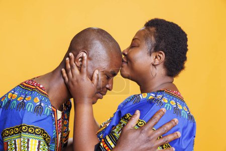 Téléchargez les photos : Femme afro-américaine embrassant mari dans le front, montrant de l'amour et des soins. Petit ami noir et petite amie montrant l'affection et la romance dans la relation tout en posant en studio - en image libre de droit