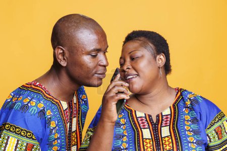 Photo for Man and woman couple using mobile phone as microphone. African american singers singing together in smartphone mic, recording song with telephone voice recorder application - Royalty Free Image
