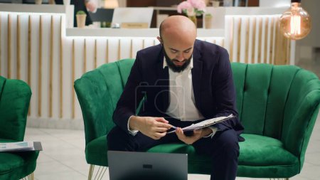 Photo for Businessman enters video call with CEO to review meeting notes and ensure perfect speech, gain respect from investors. Using online video connection to prepare for negociations. Handheld shot. - Royalty Free Image