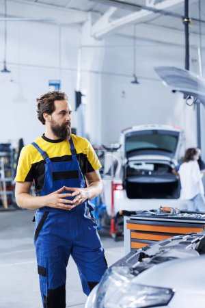 Photo for Engineer in repair shop using augmented reality holograms to check car specifications during checkup. Meticulous garage employee using futuristic AR technology to examine defective vehicle - Royalty Free Image