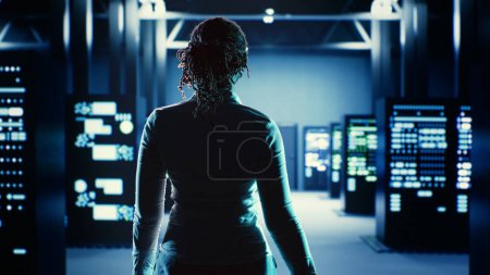Skillful employee strolling around data center server rows, looking for damages in high tech workspace equipment designed to accommodate server units, networking systems and storage arrays