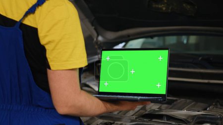 Photo for Certified mechanic using mockup laptop in car service to order new parts for damaged vehicle. Close up shot of specialist using device with isolated screen to look online for replacing components - Royalty Free Image