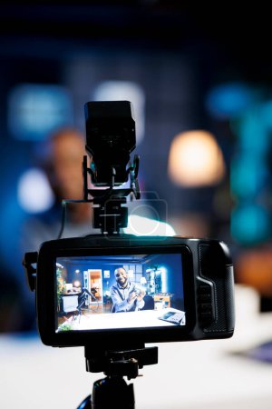 Téléchargez les photos : Focus sur la caméra professionnelle capturant des images du créateur de contenu en arrière-plan flou filmer tutoriel technique sur la façon de faire mini entretien des lumières RVB, enseigner aux téléspectateurs sur les outils de production vidéo - en image libre de droit