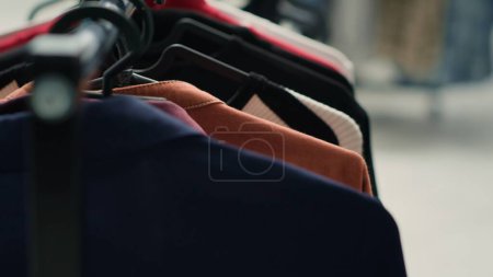 Photo for Empty premium fashion boutique with elegant clothes on racks, close up shot. High street men blazers and other garments on hangers in trendy clothing store in shopping center - Royalty Free Image
