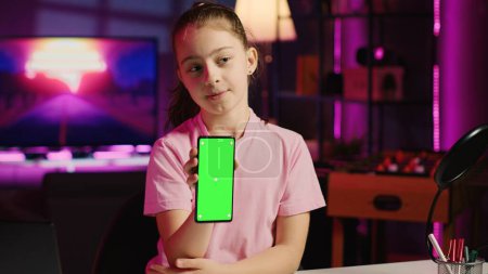 Photo for Kid content creator filming technology review of newly released green screen smartphone, unpacking it and presenting specifications to audience. Child media star showing chroma key cellphone to fans - Royalty Free Image