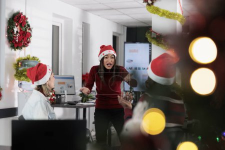Photo for Manager angry at employees, frustrated by weak company performance after checking year end analytics during Christmas season. Management executive yelling at staff members in festive decorated office - Royalty Free Image