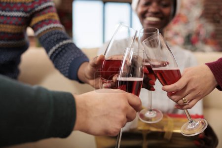 Photo for Cheerful colleagues holding beverage glasses and clinking while celebrating winter seasonal holiday together. Company workers drinking sparkling wine at christmas corporate party - Royalty Free Image