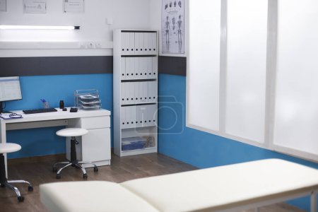 Foto de La imagen muestra una oficina clínica que se utiliza para consultas y citas. Una habitación de hospital vacía que contiene un escritorio con una computadora para un médico y una cama de examen. - Imagen libre de derechos