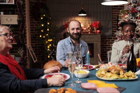 Téléchargez les photos : Adulte profitant d'hiver dîner de Noël avec divers amis, réunion avec la famille près de la cheminée pour célébrer les vacances de la veille de Noël. Les gens s'amusent pendant la célébration traditionnelle festive, décor confortable. - en image libre de droit