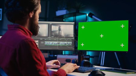 Video-Editor, der die Filmmontage auf isolierten Bildschirmen analysiert, bevor er Farbkorrektur und Beleuchtung im Kreativbüro bearbeitet. Mitarbeiter des Postproduktionsstudios arbeitet mit Rohmaterial am Chroma-Key-PC