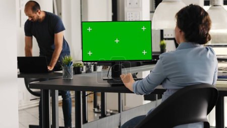 Photo for Businesswoman works with greenscreen on pc desktop, sitting in coworking space at agency office. Young adult employee reviewing computer monitor that shows isolated display with chromakey. - Royalty Free Image