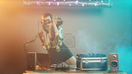 Photo for Funky dj artist mixing tunes on electronic turntables, using buttons and bass control key to mix techno sounds. Disc jockey performing with mixer at nightclub party event. Tripod shot. - Royalty Free Image