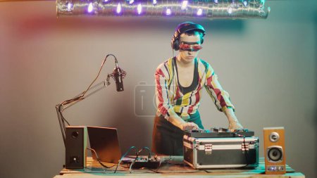 Photo for Disc jockey gives thumbs down on stage after mixing stereo sounds at turntables, showing dislike and disapproval sign while she uses mixer keys. Expressing rejection and disagreement. Tripod shot. - Royalty Free Image