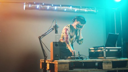 Téléchargez les photos : Femme artiste mixant des sons lors d'une fête de club avec des platines dj, en utilisant des appareils audio pour jouer de la musique et créer un remix moderne en stéréo. S'amuser avec de l'équipement disco, boîte de nuit. Coup de main. - en image libre de droit