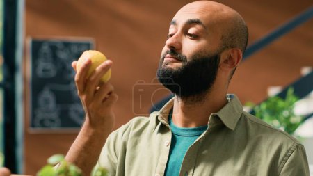 Photo for Shop owner gives lemons to client to smell and enjoy aromatic fresh citrus scent, man buying locally grown produce to support local sustainable business and storekeeper. Handheld shot. - Royalty Free Image